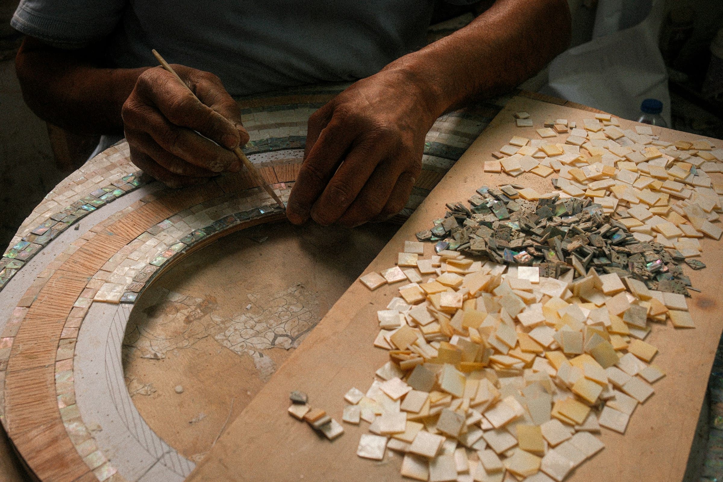 Hands laying a mosaic by hand, tile by tile